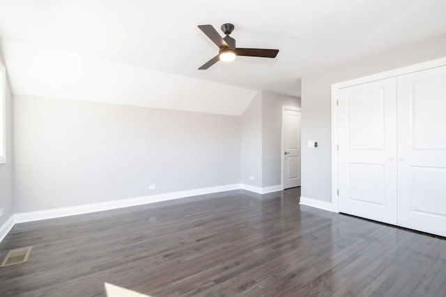 unfurnished bedroom featuring baseboards, visible vents, lofted ceiling, dark wood-style floors, and a closet