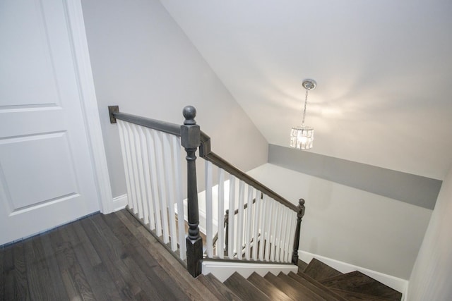 stairway featuring a chandelier, vaulted ceiling, baseboards, and wood finished floors