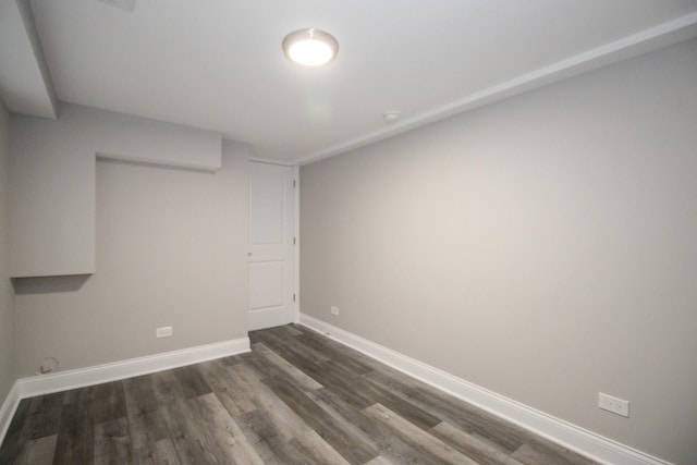 unfurnished room featuring baseboards and dark wood finished floors