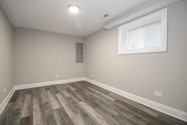 spare room featuring dark wood-style flooring, electric panel, visible vents, and baseboards