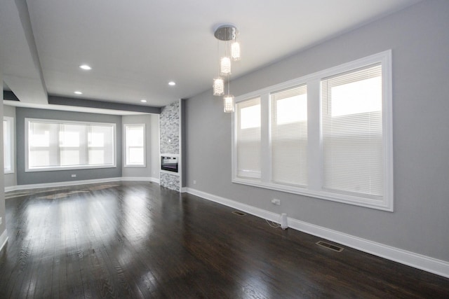 unfurnished living room featuring dark wood finished floors, recessed lighting, visible vents, a stone fireplace, and baseboards