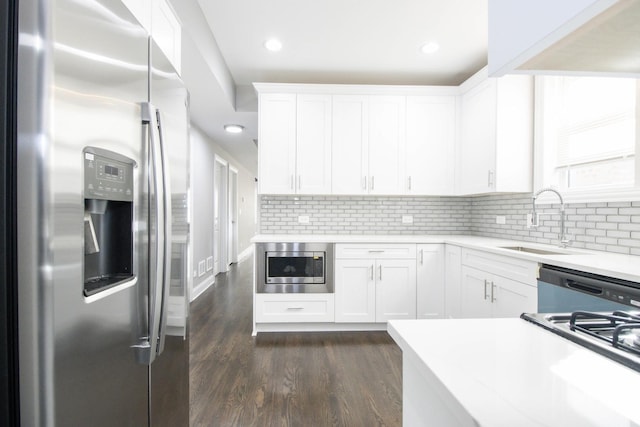 kitchen featuring dark wood-style floors, light countertops, appliances with stainless steel finishes, white cabinets, and a sink