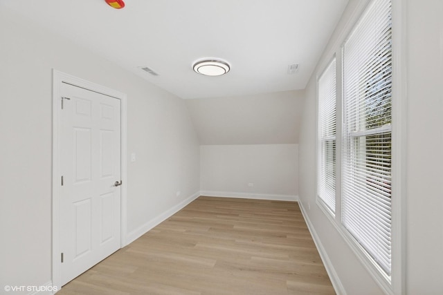 bonus room with light wood-type flooring, baseboards, and lofted ceiling