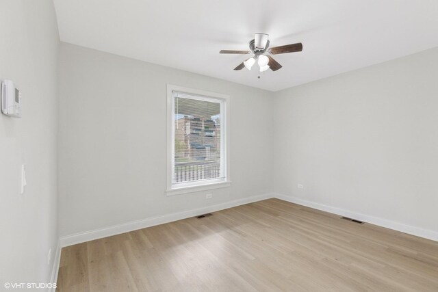 spare room featuring light wood-type flooring, baseboards, and ceiling fan