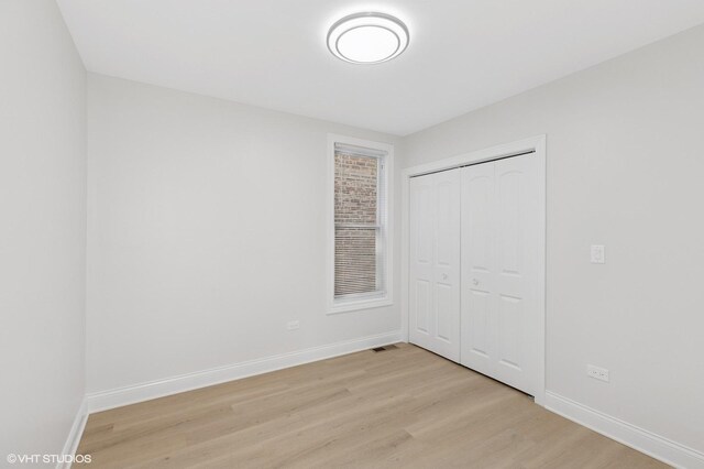 unfurnished bedroom with light wood-type flooring, baseboards, and a closet
