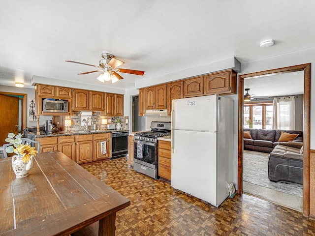 kitchen featuring appliances with stainless steel finishes, brown cabinetry, and a ceiling fan