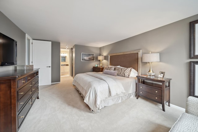 bedroom featuring ensuite bathroom and light colored carpet