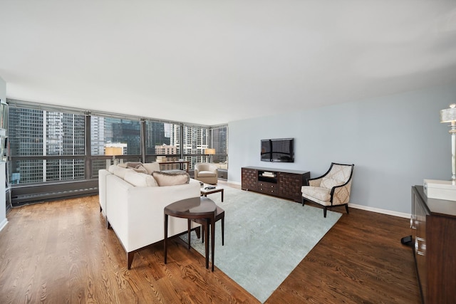 living room with a baseboard heating unit, floor to ceiling windows, baseboards, and wood finished floors