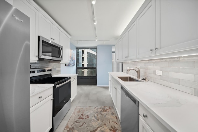 kitchen with stainless steel appliances, a sink, white cabinetry, and decorative backsplash