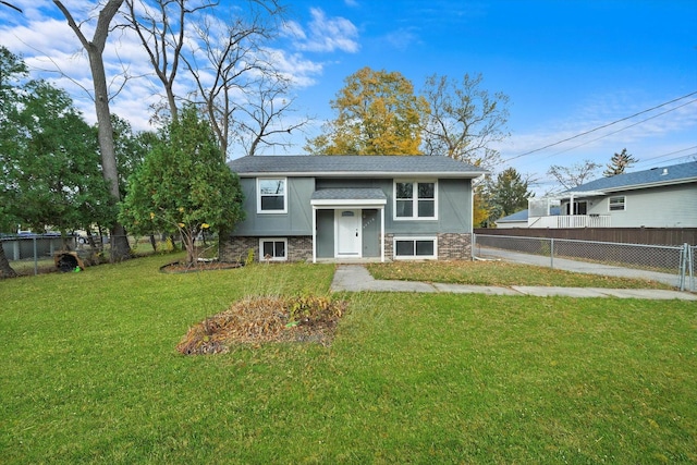 split foyer home with roof with shingles, a front yard, and fence private yard