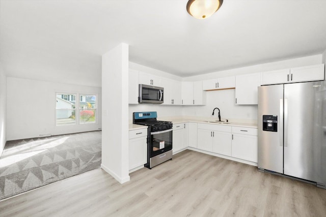 kitchen with light countertops, appliances with stainless steel finishes, a sink, and white cabinetry