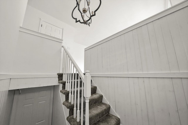 staircase with a notable chandelier