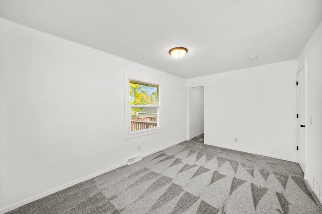 carpeted empty room featuring baseboards and visible vents