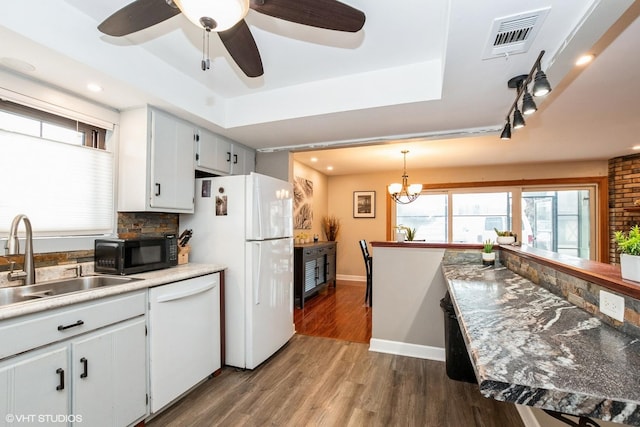 kitchen featuring white appliances, dark wood-style flooring, a raised ceiling, and visible vents