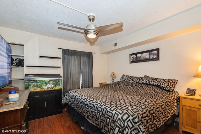 bedroom with dark wood-style floors, visible vents, a textured ceiling, and a ceiling fan