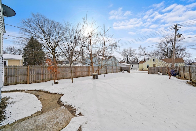 snowy yard featuring a fenced backyard and a residential view