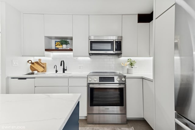 kitchen with stainless steel appliances, white cabinets, and light stone countertops