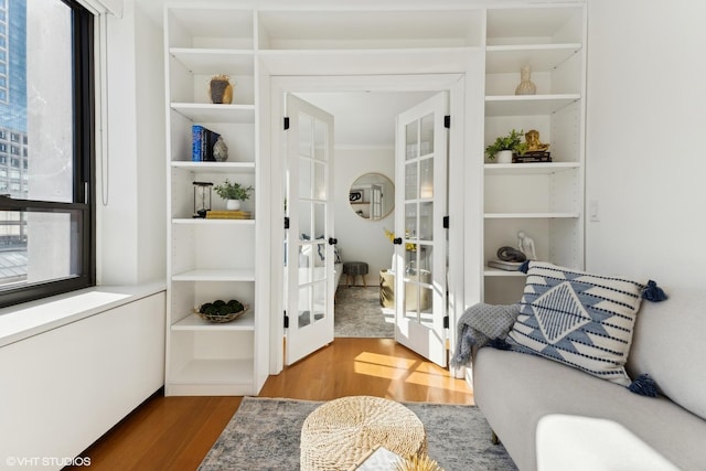 sitting room featuring french doors, wood finished floors, and built in shelves