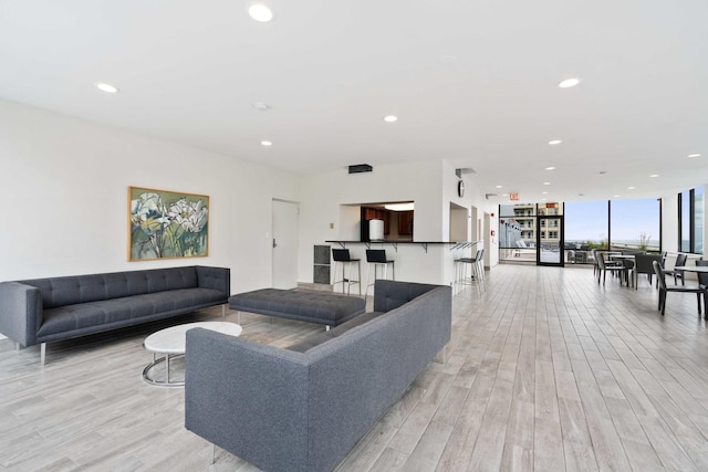 living area featuring a wall of windows, light wood-style flooring, and recessed lighting