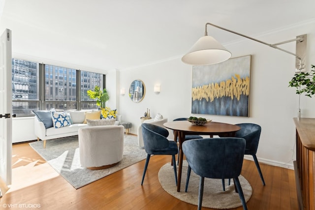 dining space featuring ornamental molding, wood finished floors, and baseboards