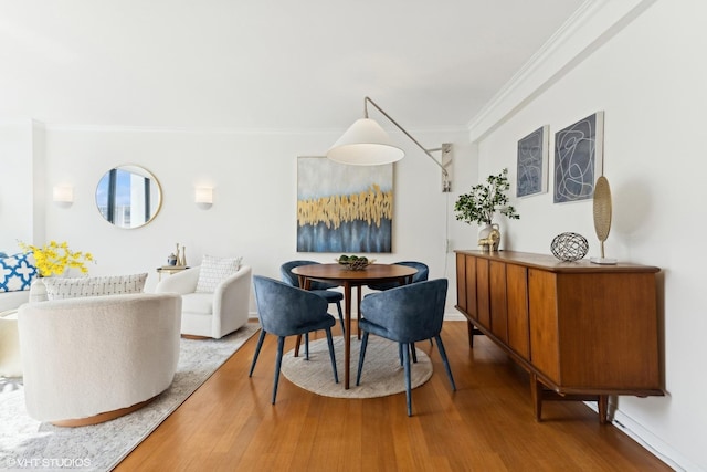 dining area with ornamental molding and wood finished floors