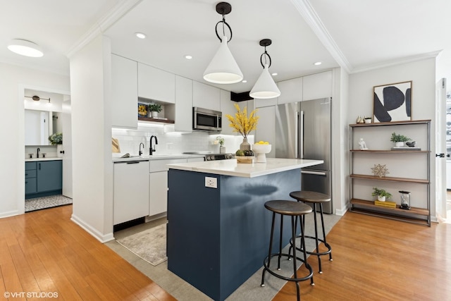 kitchen featuring appliances with stainless steel finishes, a center island, white cabinets, and decorative light fixtures