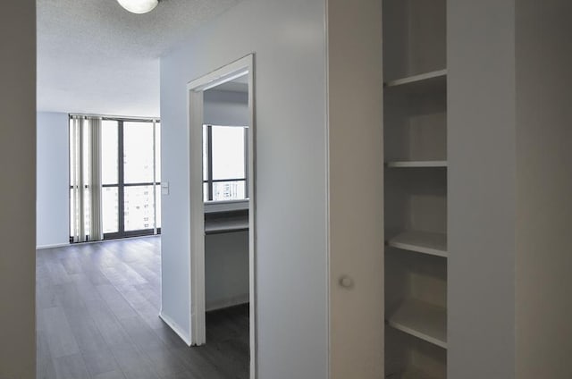 hallway featuring a textured ceiling, dark wood-style flooring, and built in features