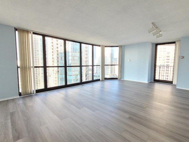 unfurnished living room with a wealth of natural light, floor to ceiling windows, and wood finished floors