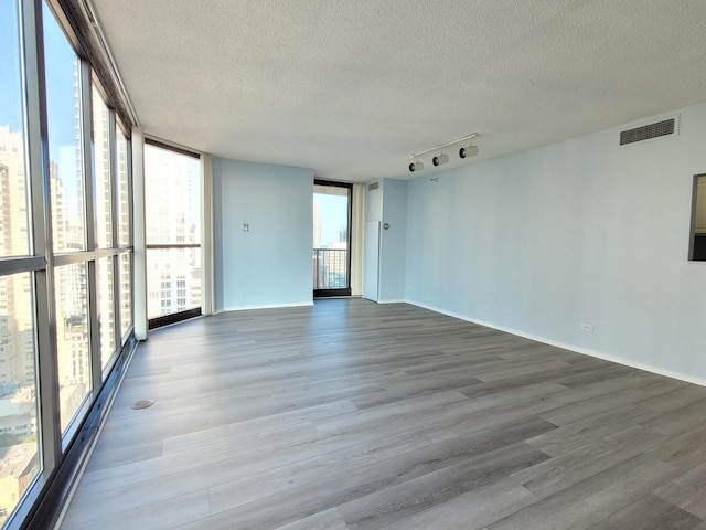 spare room featuring a wall of windows, visible vents, a textured ceiling, and wood finished floors