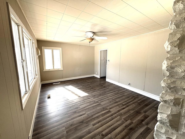 spare room with dark wood-style floors, visible vents, baseboards, and a ceiling fan