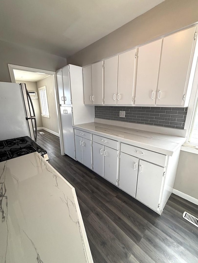 kitchen with light countertops, freestanding refrigerator, white cabinets, and tasteful backsplash