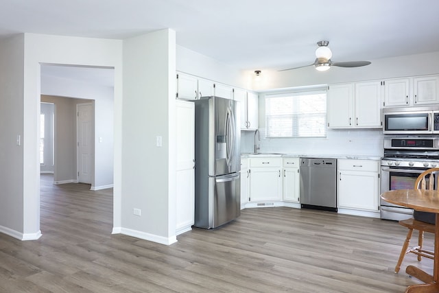 kitchen featuring a sink, stainless steel appliances, light countertops, and white cabinets