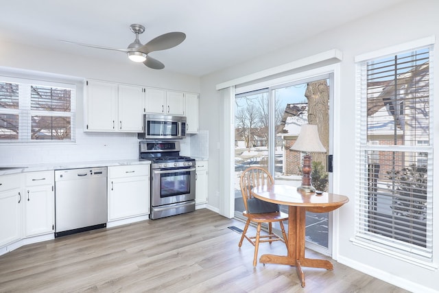 kitchen featuring stainless steel appliances, a wealth of natural light, white cabinets, and light countertops