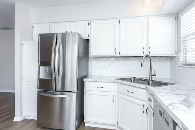 kitchen featuring tasteful backsplash, white cabinets, a sink, and stainless steel fridge with ice dispenser