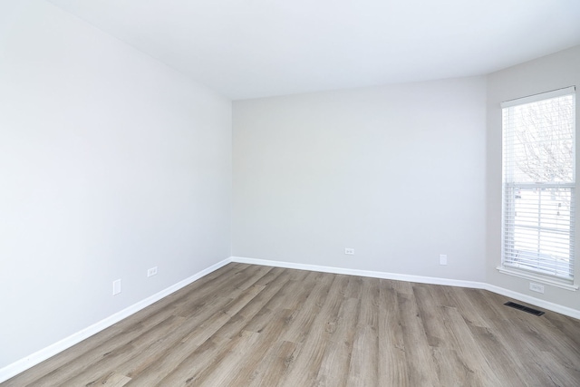 unfurnished room featuring light wood finished floors, baseboards, and visible vents