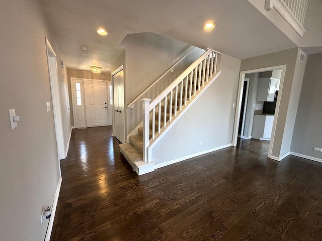 foyer featuring dark wood-type flooring, recessed lighting, baseboards, and stairs