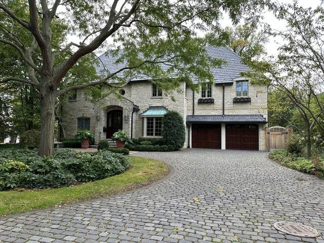 view of front of home with a high end roof, decorative driveway, a garage, and stone siding