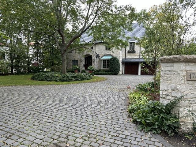 view of front of home featuring stone siding, a high end roof, decorative driveway, and a garage