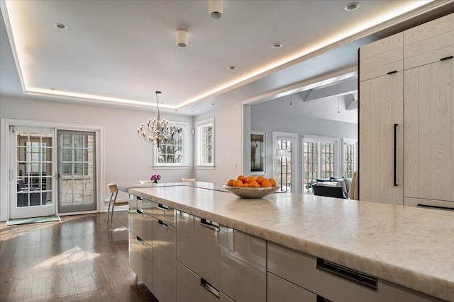 kitchen featuring pendant lighting, french doors, light countertops, a raised ceiling, and dark wood-style flooring