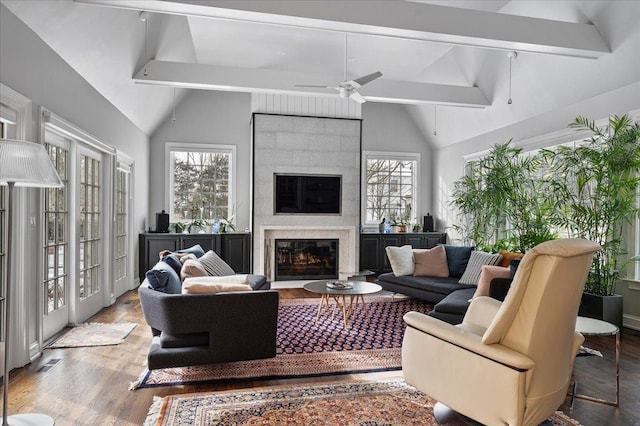 living room with beam ceiling, plenty of natural light, wood finished floors, and a fireplace