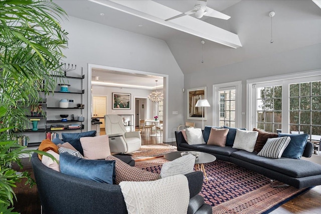 living area featuring wood finished floors, ceiling fan with notable chandelier, and high vaulted ceiling