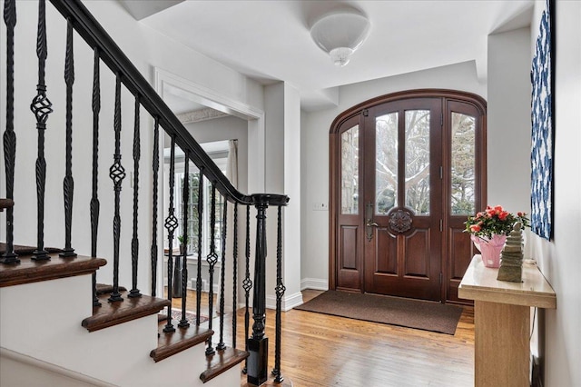 entryway with arched walkways, baseboards, and wood finished floors