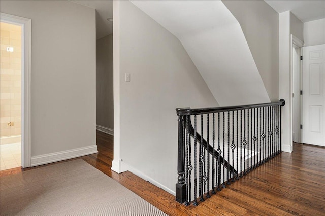 hallway featuring an upstairs landing, baseboards, and wood finished floors