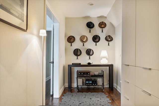 corridor featuring baseboards and dark wood-style floors