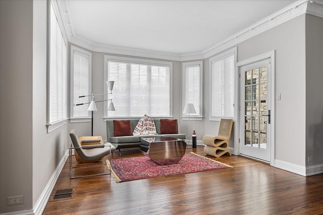 living area with visible vents, crown molding, baseboards, and hardwood / wood-style floors