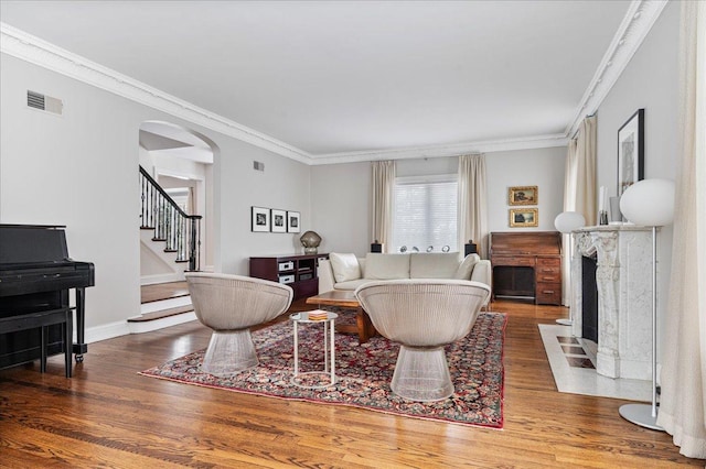 living room featuring visible vents, wood finished floors, a high end fireplace, stairway, and arched walkways