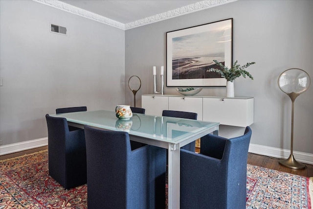 dining space with visible vents, baseboards, wood finished floors, and ornamental molding