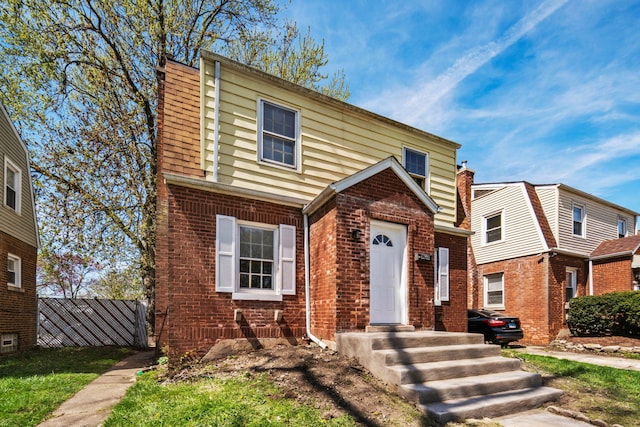 view of front of house featuring brick siding and fence