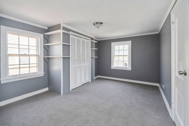 unfurnished bedroom featuring ornamental molding, a closet, carpet, and baseboards