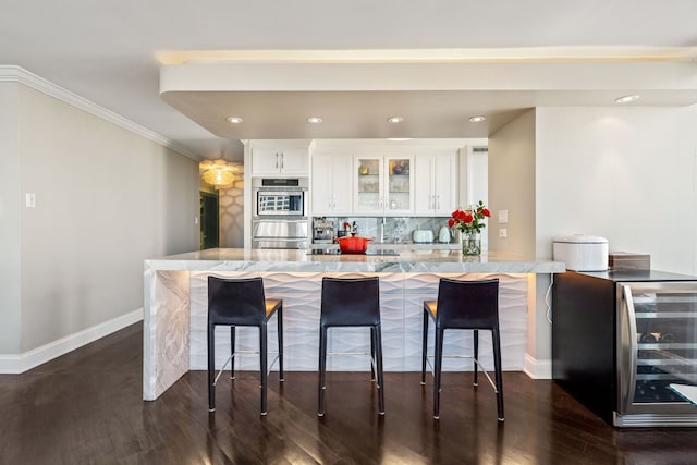 kitchen with wine cooler, white cabinets, backsplash, and a breakfast bar area